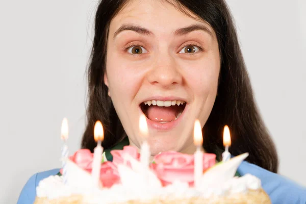 Una doctora con uniforme azul sostiene un pastel de cumpleaños con velas y sonrisas. —  Fotos de Stock