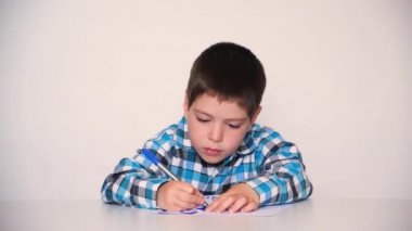A preschool child in a plaid shirt draws a drawing, paints with a blue marker