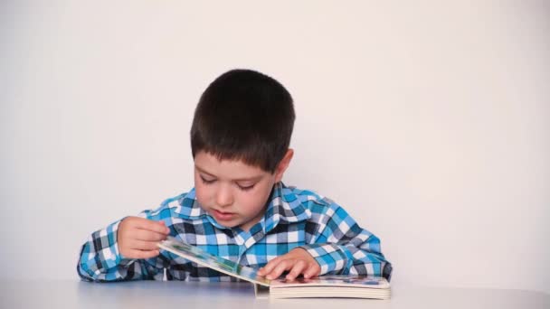 Un niño en edad preescolar lee un libro, lo cierra y lo aleja de sí mismo. — Vídeos de Stock