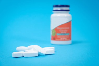 Bir kavanoz diyet takviyesi ve mavi arka planda beyaz haplar, mesaj için bir yer. Tam bir diyet için vitamin ve eser elementler
