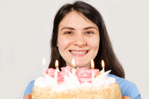 Una doctora con uniforme azul sostiene un pastel de cumpleaños con velas y sonrisas. —  Fotos de Stock