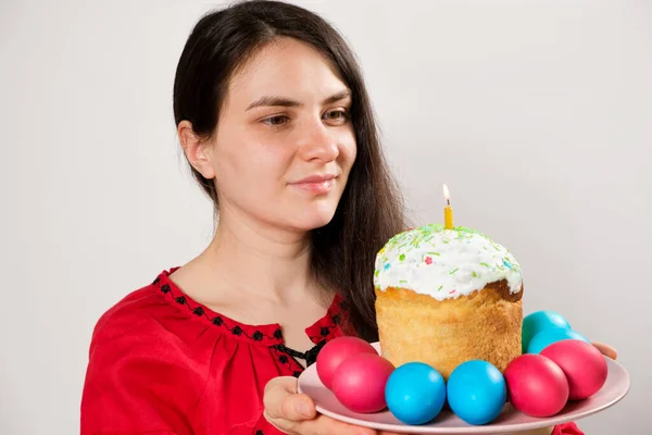 A woman holds an Easter cake and painted eggs on a white background, copy space for text. —  Fotos de Stock