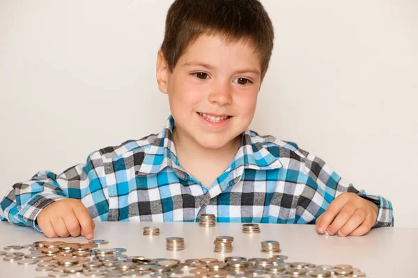 A preschool boy in a plaid shirt counts coins, builds towers. Financial literacy for children. — Stock fotografie