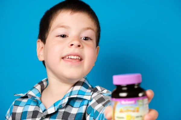 4 yaşındaki bir çocuk elinde bir kavanoz D vitamini ya da diyet takviyesi tutuyor.