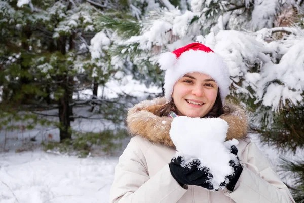 Kobieta Kapeluszu Mikołaja Trzyma Śnieżkę Dłoniach Zimowym Lesie Pokrytym Śniegiem — Zdjęcie stockowe