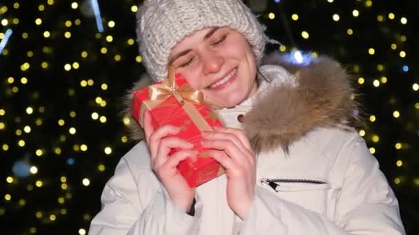 Een Gelukkige Vrouw Grijpt Een Geschenk Glimlacht Buiten Een Kerstboom — Stockvideo