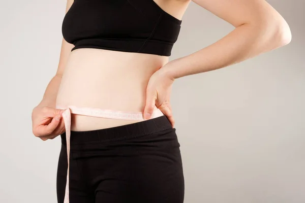 一个女人用一厘米长的带子 近距离测量腹部的周长 瘦身的概念 — 图库照片
