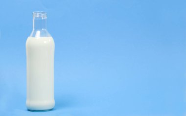 Mavi arka planda cam bir süt şişesi ve metin için yer var.