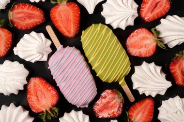 Siyah arka planda iki kremalı ve çilekli dondurma, üst tarafta. Lezzetli yiyecek ve meyvelerle dolu parlak bir yaz kartı.