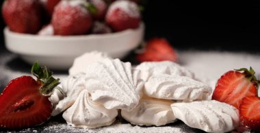 Kremalı pasta yakın plan ve siyah arka planda çilekler. Meyve tatlısı