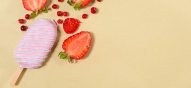 Çubuklu pembe dondurma, içinde çilek ve bej arka planda kırmızı yaban mersini ve mesaj için yer var..