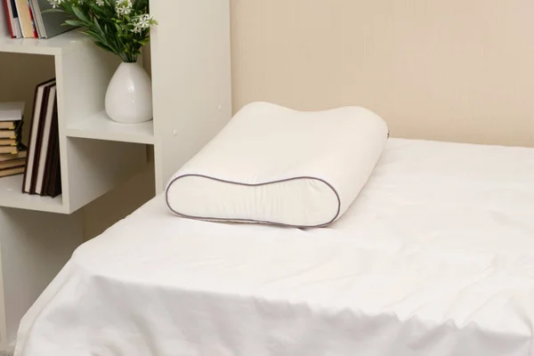 White orthopedic memory foam pillow on the bed. Comfortable pillow for healthy sleep