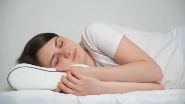 女は枕の上にゆったりと横になろうとする 健康な睡眠のための右の枕の選択 — ストック動画