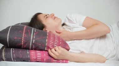 Bir kadın uyumaya çalışır, boynu ağrır ve rahat bir ortopedik yastığa uzanır..