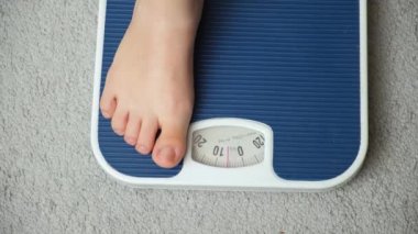 Kadınların bacakları terazinin üzerinde duruyor, pulların okları 50 kilogramdan fazla gösteriyor.