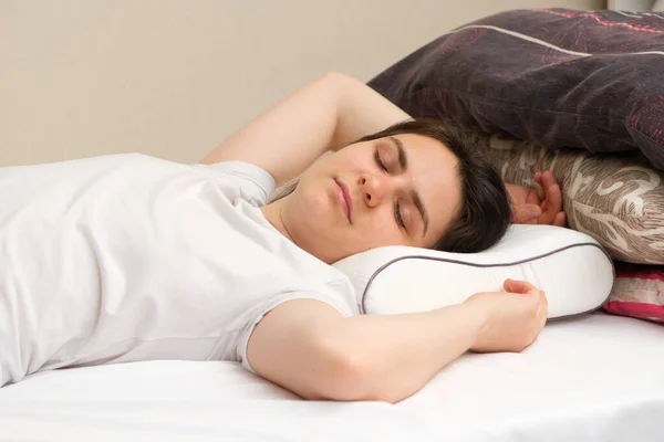 A woman sleeps on an orthopedic pillow made of memory foam, choosing it instead of other pillows made of fluff and sintepon.