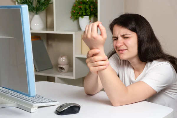女性はコンピュータの前に座って手首に手を握り手首に痛みトンネル症候群 — ストック写真