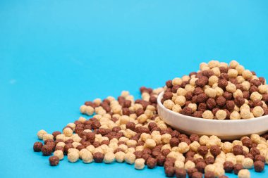 Mavi arka planda mısır gevreği ve mesaj yeri. Hızlı kuru kahvaltı, yan görünüm