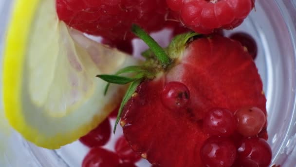 将水倒入含有草莓 柠檬和冰块的夏季鸡尾酒的过程 — 图库视频影像