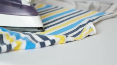 The process of ironing a childrens striped T-shirt. Care for clothes.