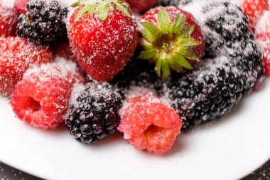 Raspberries, strawberries and blackberries sprinkled with sugar, close-up