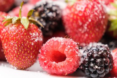 Raspberries, strawberries and blackberries sprinkled with sugar, close-up