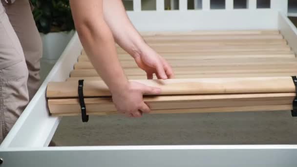 Man Assembles Childrens Wooden Bed Installs Slats — стоковое видео