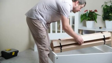 A man assembles a childrens wooden bed, installs slats