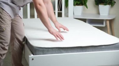 A man checks the stiffness of a new comfortable mattress