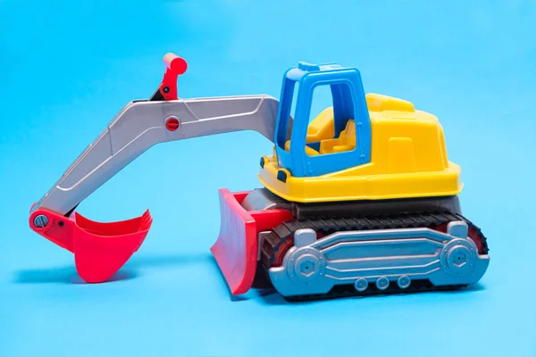Yellow excavator plastic car on blue background. Construction machinery car for digging for toy store and children