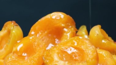 Bal, kayısı dilimlerinin üzerine dökülür. Siyah arka planda ballı lezzetli meyveler.