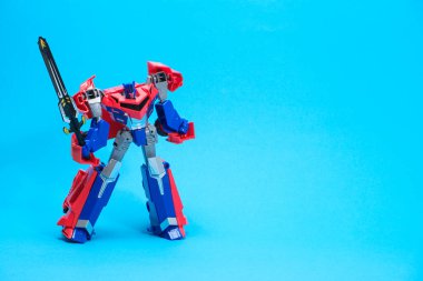 Mavi arka planda kırmızı robot transformatörü ve metin için yeri var. Çocuklar için oyuncaklar, oyuncakçılar.