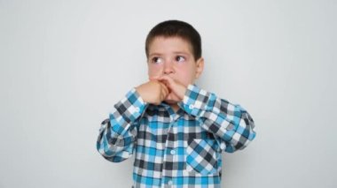 A preschool boy eats carrots standing on a white background.