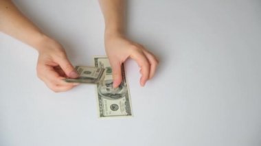 A woman counts dollar bills for 100 dollars on a white background, top view