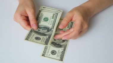 A woman counts dollar bills for 100 dollars on a white background, top view
