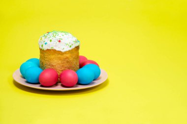 Easter cake and painted eggs on a yellow background, copy the place for the text.
