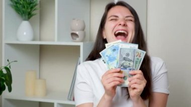 A happy woman throws up a lot of bills of dollars and euros and laughs