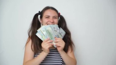 Funny silly woman with two ponytails has fun holding a lot of money, throws them up