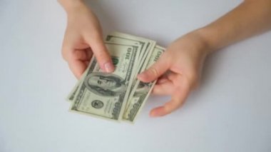 A woman counts dollar bills for 100 dollars on a white background, top view.