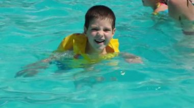 A 5-year-old boy is learning to swim in an inflatable vest in a pool