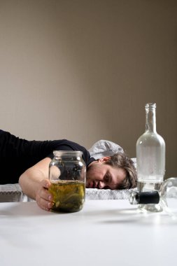 Alkol bağımlısı bir adam yatağa uzanır ve elini bir kavanoz salatalık salamurasına uzatır. Akşamdan kalmalık için halk ilaçları..