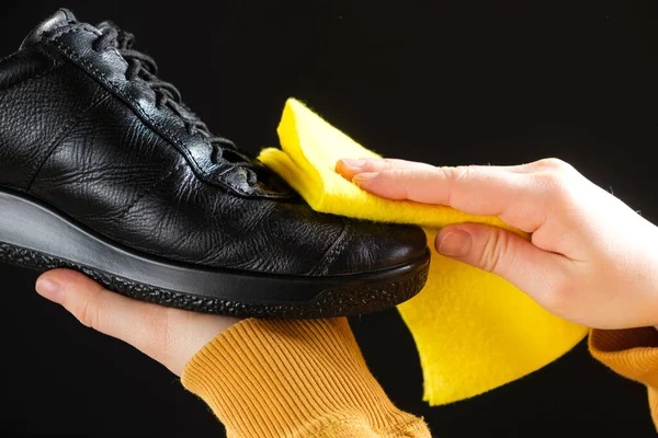 A man wipes leather men\'s black shoes with a yellow shoe rag. Cleaning from dust, shoe care.