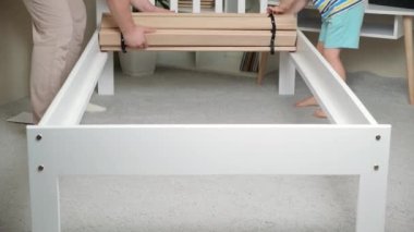 Father and son together assemble a childrens bed, installs slats