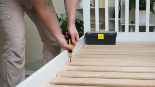 家具装配工把床组装好 把螺丝拧在木板板上 用特写螺丝刀手 — 图库视频影像
