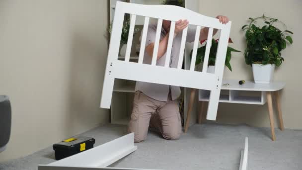 Man Assembles Body Childrens Wooden Bed — Vídeos de Stock