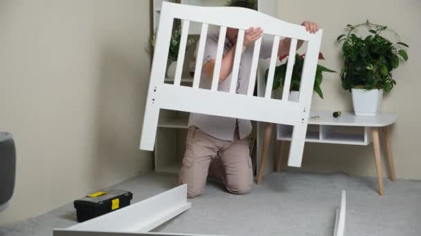 Man Assembles Body Childrens Wooden Bed — 图库视频影像