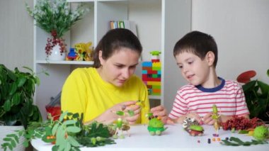 A mother with a 5-year-old son makes autumn crafts from acorns, chestnuts and cones