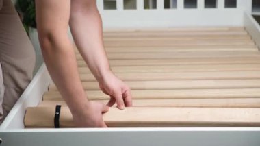 A man assembles a childrens wooden bed, installs slats
