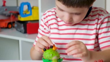 A 5-year-old boy plays with a chestnut hedgehog figure. Autumn crafts with your own hands.