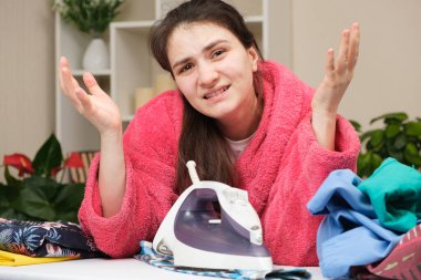 Yorgun eş bir ütüyle elbiselerini ütüleyecek. Ev ödevinden dolayı yorgunluk..